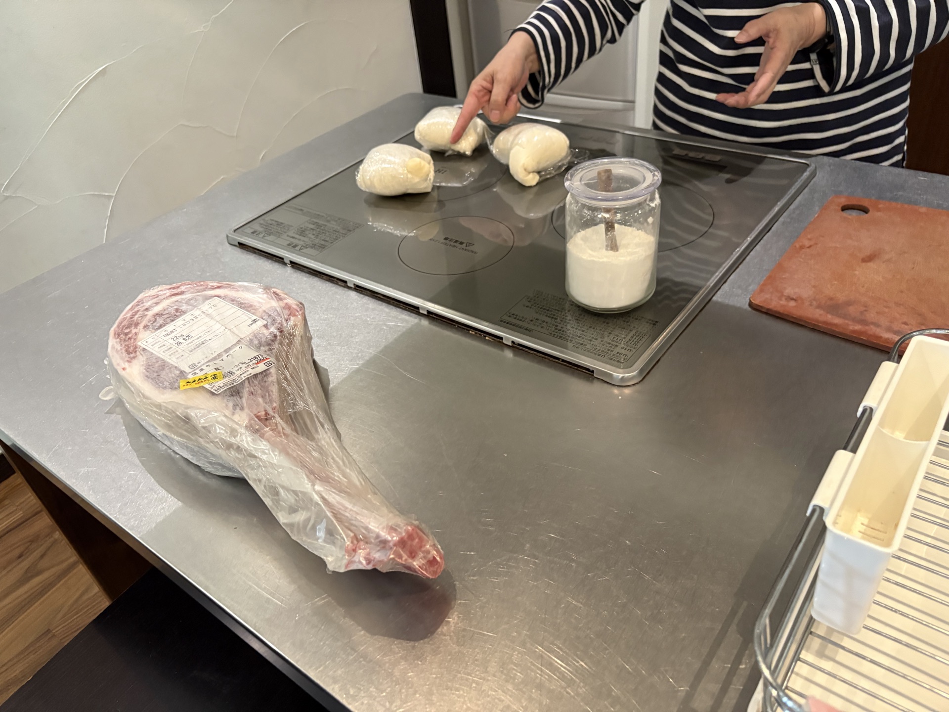 貸別荘のキッチンでピザ生地を仕込む様子。手前にトマホークステーキ