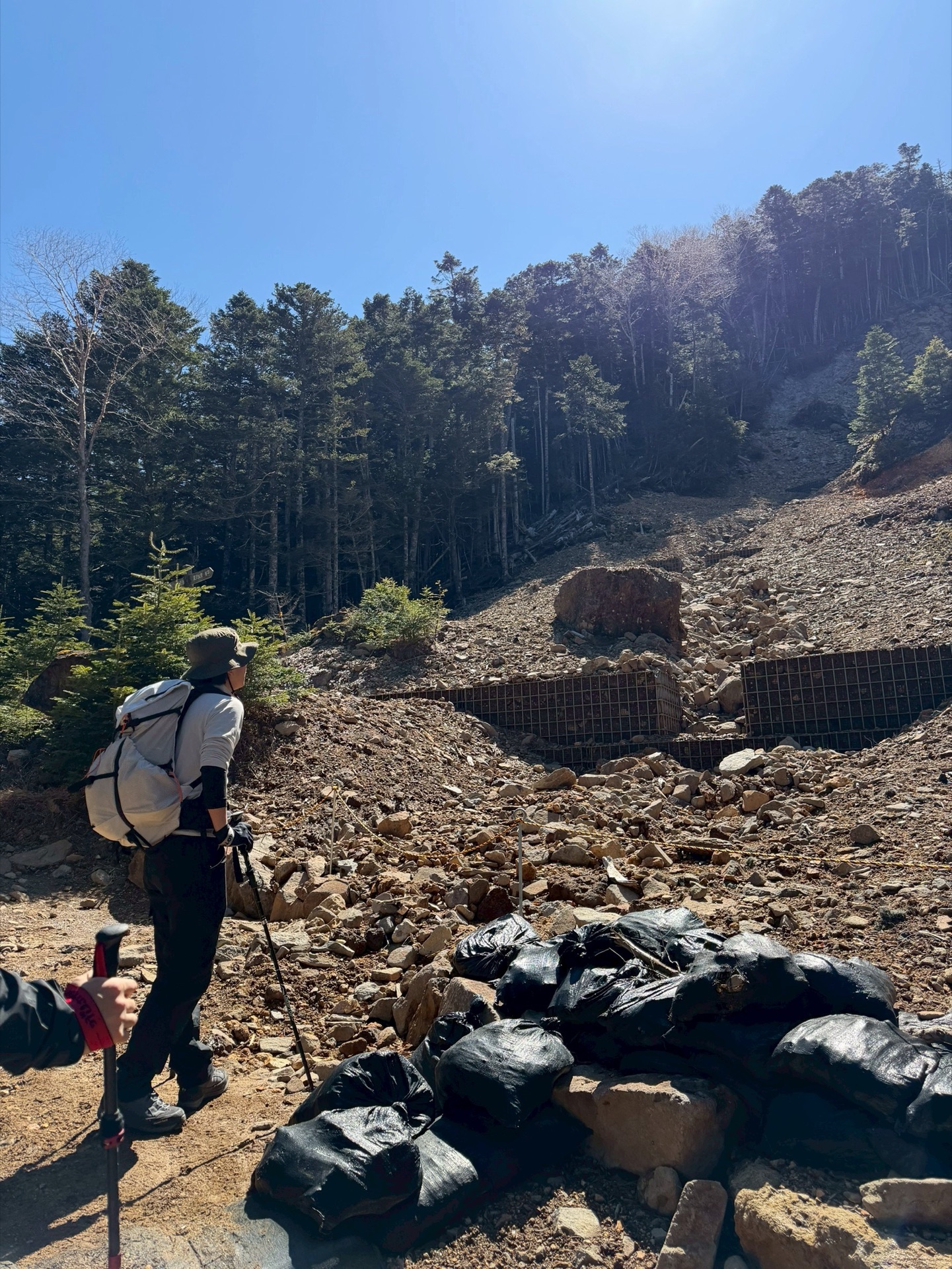 硫黄岳・桜平ルート序盤にある砂防堰堤を見上げる登山者