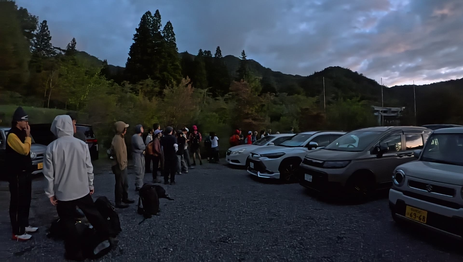 早朝の駐車場で乗合バスを待つ登山者の行列